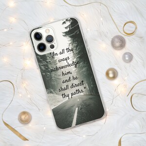 Op de afbeelding: Een transparante telefoonhoes met een zwart-witfoto van een weg door een bos. De tekst "In all thy ways acknowledge him, and he shall direct thy paths." staat op de hoes gedrukt.