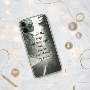 Op de afbeelding: Een transparante telefoonhoes met een zwart-witfoto van een weg door een bos. De tekst "In all thy ways acknowledge him, and he shall direct thy paths." staat op de hoes gedrukt.