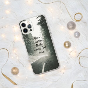 Op de afbeelding: Een transparante telefoonhoes met een zwart-witfoto van een weg door een bos. De tekst "Your Custom Bible verse/Text here." is op de hoes gedrukt.