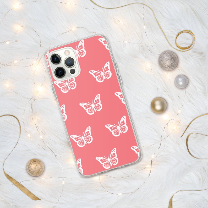 Puede incluir: Una funda de tel&eacute;fono transparente con fondo rosa y un patr&oacute;n de mariposas blancas.