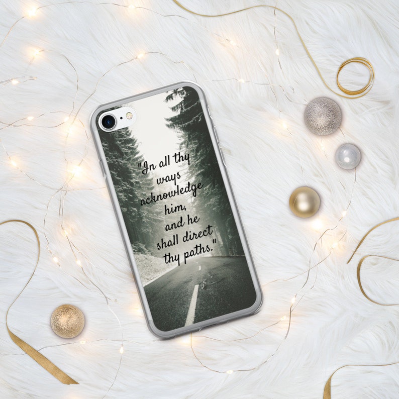 Op de afbeelding: Een transparante telefoonhoes met een zwart-witfoto van een besneeuwde weg met bomen aan weerszijden. De tekst "In all thy ways acknowledge him, and he shall direct thy paths." staat op de hoes gedrukt.