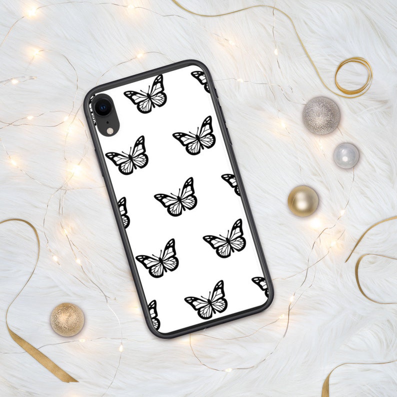 Puede incluir: Una funda de tel&eacute;fono negra con fondo blanco y un patr&oacute;n repetitivo de mariposas negras.