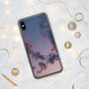 May include: A clear phone case with a pink and blue sky with stars and a crescent moon printed on the back.