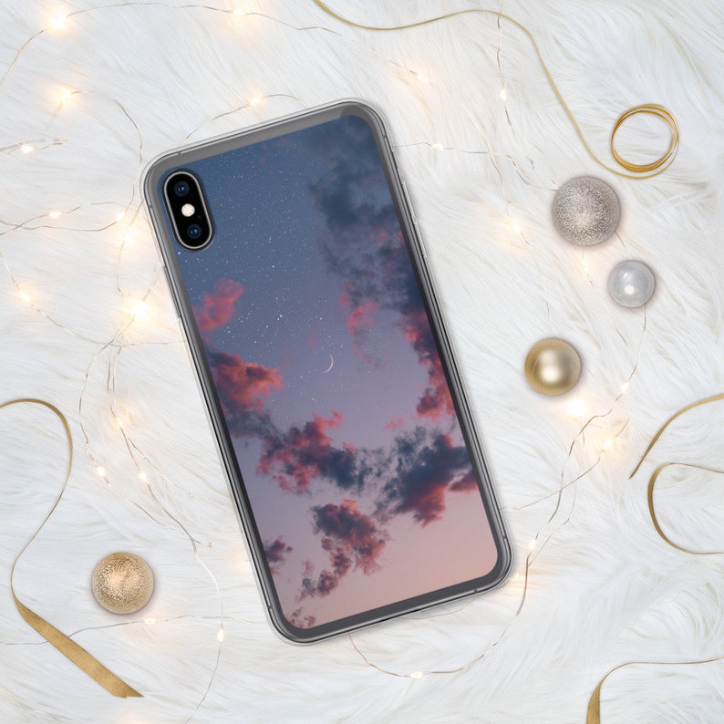 May include: A clear phone case with a pink and blue sky with stars and a crescent moon printed on the back.