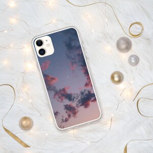 May include: A clear phone case with a pink and purple cloudy sky with stars and a crescent moon printed on it.