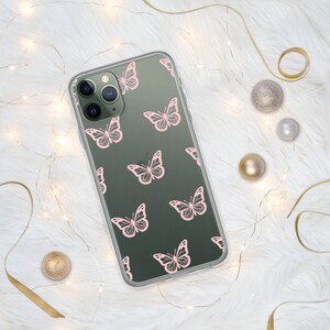 Puede incluir: Una funda transparente para tel&eacute;fono con fondo verde oscuro y un patr&oacute;n de mariposas rosas. La funda est&aacute; dise&ntilde;ada para un iPhone con una c&aacute;mara de triple lente.