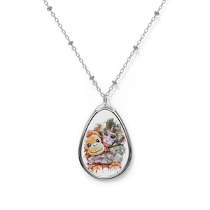 May include: Silver-toned necklace with a teardrop pendant. The pendant features a watercolor-style image of a monkey hugging a stuffed animal. The monkey has gray and brown fur, and the stuffed animal is orange. The chain is a delicate link style.