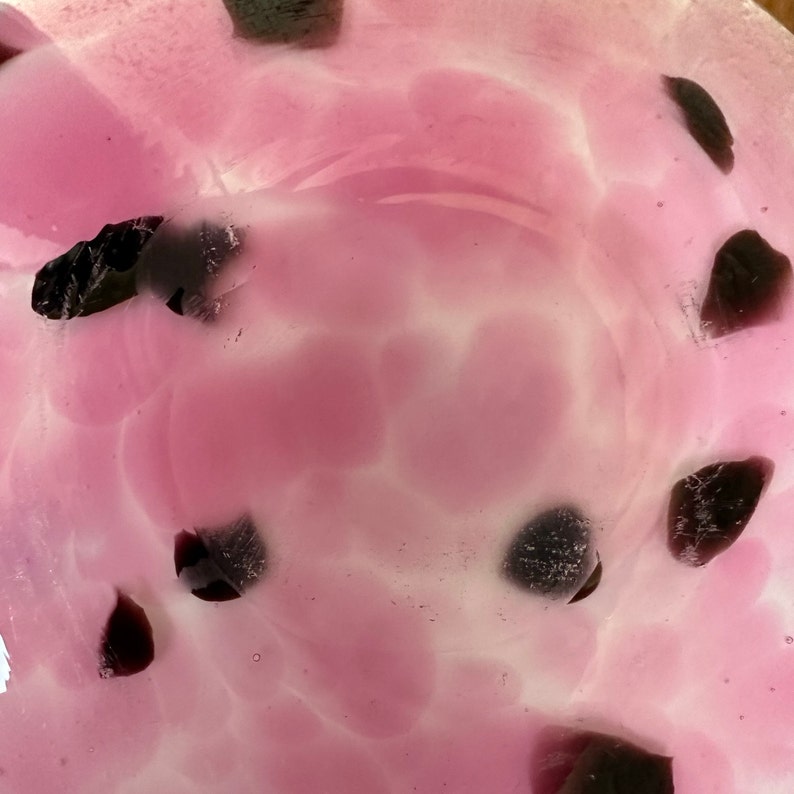 Puede incluir: Un cuenco de vidrio hecho a mano con un dise&ntilde;o rosa y blanco, acentuado con piezas de vidrio p&uacute;rpura oscuro. El interior del cuenco presenta un patr&oacute;n arremolinado, creando una apariencia art&iacute;stica &uacute;nica. Este cuenco decorativo es ideal para exhibir objetos peque&ntilde;os o como pieza de arte independiente.