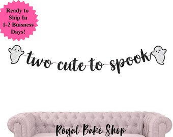 Könnte beinhalten: Ein schwarzes Glitzerbanner mit dem Schriftzug "two cute to spook" in Schreibschrift, flankiert von zwei glitzernden Geisterfiguren. Das Banner ist vor einem weißen Hintergrund gespannt. Eine rosa Stern-Grafik zeigt "Ready to Ship In 1-2 Buisness Days!"