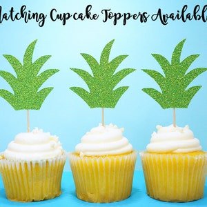Puede incluir: Tres cupcakes amarillos con glaseado blanco cubiertos con adornos de cupcake de pi&ntilde;a verde con purpurina. Los adornos est&aacute;n hechos de cartulina y tienen un acabado brillante. Los cupcakes est&aacute;n sobre un fondo azul claro. &iexcl;Adornos de cupcake a juego disponibles!