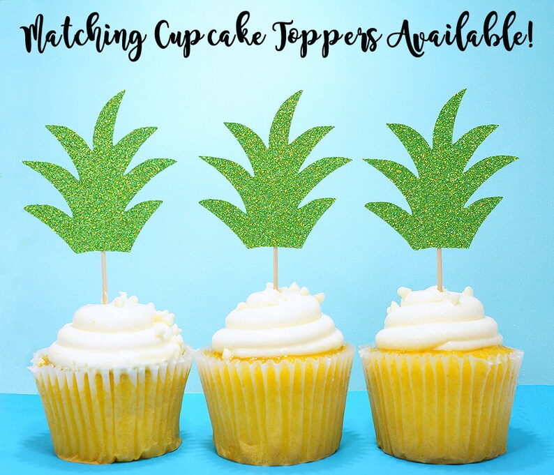 Puede incluir: Tres cupcakes amarillos con glaseado blanco cubiertos con adornos de cupcake de pi&ntilde;a verde con purpurina. Los adornos est&aacute;n hechos de cartulina y tienen un acabado brillante. Los cupcakes est&aacute;n sobre un fondo azul claro. &iexcl;Adornos de cupcake a juego disponibles!