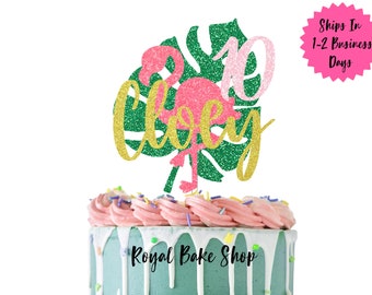 Könnte beinhalten: Ein grünes Glitzer-Tropenblatt mit einem rosafarbenen Glitzer-Flamingo und goldenen Glitzer-Buchstaben, auf dem "10 Today" steht.