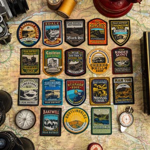 K&ouml;nnte beinhalten: Eine Sammlung gestickter Aufn&auml;her mit verschiedenen Orten im Peak District, wie Edale und Mam Tor. Die Aufn&auml;her, in verschiedenen Formen, zeigen Texte und Illustrationen in Farben wie Blau und Gr&uuml;n. Sie sind auf einer Karte angeordnet.