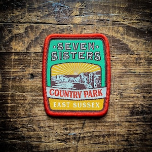 May include: An embroidered patch with the text "Seven Sisters Country Park East Sussex" in red, green and yellow.