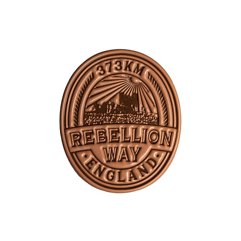 K&ouml;nnte beinhalten: Runde, bronzefarbene Medaille mit der Aufschrift "REBELLION WAY ENGLAND" und "373KM". Das Design beinhaltet eine stilisierte Illustration eines Geb&auml;udes und Sonnenstrahlen. Die Medaille hat einen erhabenen Rand.