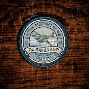May include: A circular embroidered patch featuring a light blue background with a green and grey De Havilland Mosquito aircraft. The text reads BRITISH AIRCRAFT OF WWII, DE HAVILLAND, and MOSQUITO. The patch has a dark blue border and stitching.