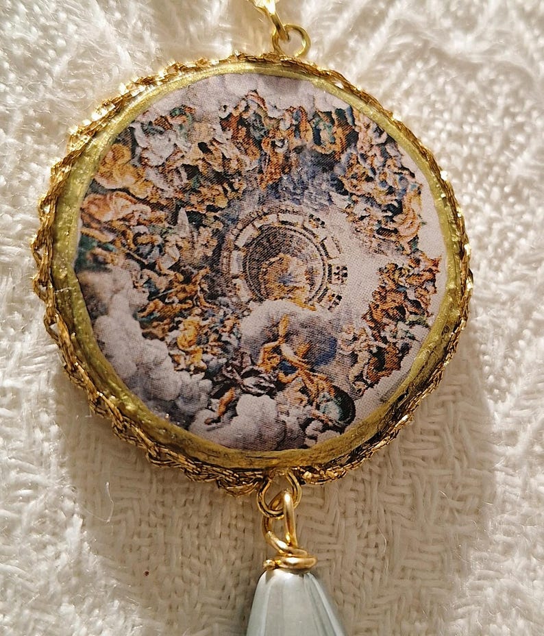 Immagine rappresenta il particolare centrale di uno degli orecchini. L'immagine rotonda è incorniciata da una piccola passamaneria in filo dorato.
Il dipinto raffigura il celebre affresco presente nel soffitto di Palazzo te a Mantova, dal titolo la Caduta dei Giganti