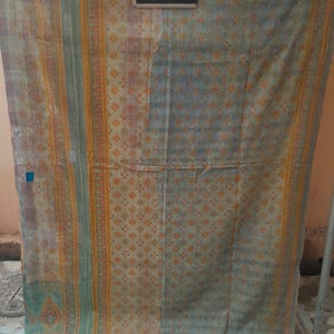 Puede incluir: Textil vintage con un dise&ntilde;o descolorido y estampado. La tela presenta una mezcla de colores, incluyendo azul, naranja y verde, con un patr&oacute;n geom&eacute;trico repetitivo. El texto "7352" es visible en una peque&ntilde;a pizarra adjunta al textil.