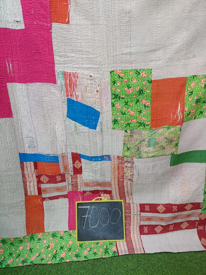 Puede incluir: Una colcha de retazos con una variedad de colores y patrones, incluyendo rosa, rojo, verde, azul y blanco. La colcha est&aacute; hecha de diferentes telas y texturas, y tiene un aspecto r&uacute;stico y hecho a mano. Un peque&ntilde;o letrero de pizarra con el precio "7000" est&aacute; en la esquina inferior derecha de la imagen.