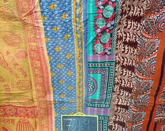 May include: A colourful patchwork textile featuring a mix of patterns. The design includes floral, paisley, and geometric motifs in blue, brown, red, and yellow. A small chalkboard with the number "7219" is in the center.