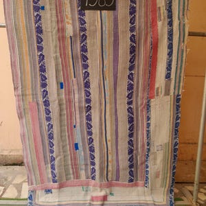 Könnte beinhalten: Ein mehrfarbiges Textil mit vertikalen Streifen und Patchwork-Design. Die Farben umfassen Rosa, Lila, Blau und Beige. Die Zahl "7383" steht auf einem kleinen Etikett. Das Design ist eine Mischung aus Mustern und Texturen.