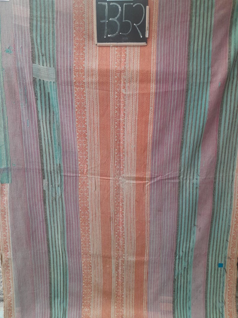 Puede incluir: Textil multicolor con rayas verticales en tonos naranja, morado y turquesa. La tela tiene un aspecto texturizado con una mezcla de rayas lisas y estampadas. Una peque&ntilde;a pizarra con el n&uacute;mero "7352" est&aacute; en la esquina superior derecha.