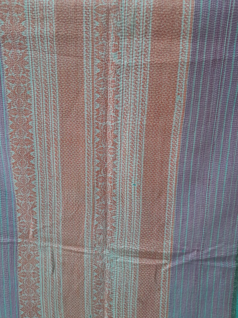 Puede incluir: Textil con un patr&oacute;n de rayas en tonos marr&oacute;n, verde azulado y morado. La tela presenta rayas verticales con dise&ntilde;os florales y geom&eacute;tricos. La textura general parece suave y posiblemente cosida a mano, lo que sugiere un art&iacute;culo artesanal.