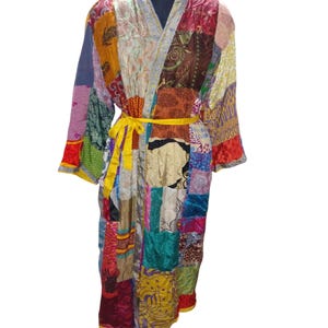 Pode incluir: Uma longa bata de patchwork colorida com uma faixa amarela. A bata é feita de vários tecidos e padrões, incluindo desenhos florais, geométricos e paisley.