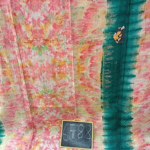 Op de afbeelding: Een kleurrijk kantha-deken met een tie-dye-patroon in tinten roze, oranje en groen. Het deken heeft een donkergroene rand en een klein krijtbord met het nummer 688 erop.