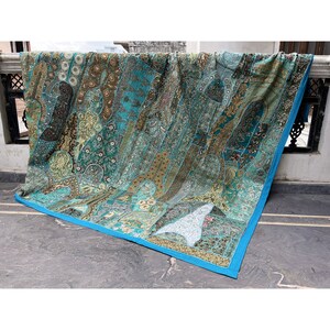 May include: A large, colorful patchwork quilt with a turquoise border. The quilt is made of various fabrics and textures, including velvet, satin, and embroidery. The quilt is decorated with sequins and beads.