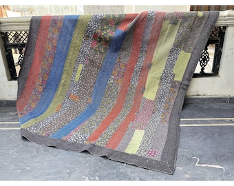 Puede incluir: Una colcha de retazos colorida con rayas de tela roja, azul, verde y amarilla. La colcha está hecha de diferentes patrones y texturas, creando un diseño único y llamativo.
