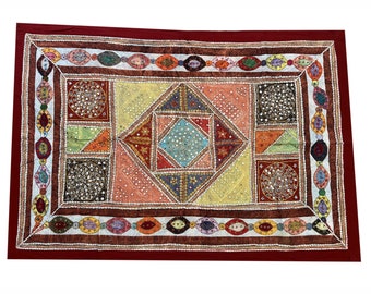 May include: A colorful patchwork quilt with a geometric design. The quilt is made of various fabrics and is decorated with sequins and mirrors. The quilt is framed by a red border.