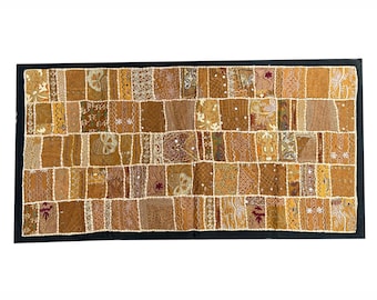May include: A brown patchwork wall tapestry with a black border. The tapestry is made of many different fabrics and textures, and it has a rustic, bohemian feel.