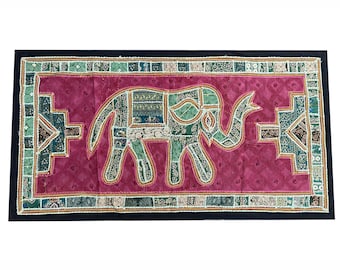 May include: A pink and green tapestry with an embroidered elephant design. The elephant is made of patchwork fabric and has a beaded border.