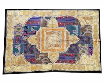 May include: A colorful patchwork throw pillow with a geometric design in shades of purple, gold, and brown. The pillow has a black border and is decorated with intricate embroidery.