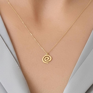 May include: A delicate gold necklace featuring a spiral pendant. The pendant is suspended from a fine chain, resting against a gray shirt. The necklace is a simple yet elegant piece of jewelry.