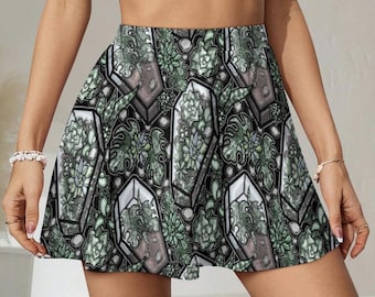 May include: A-line skirt with a repeating pattern of stylized coffins filled with succulents and other plants. The design incorporates shades of green, grey, and white against a black background. The skirt has a flared silhouette and a high waist.