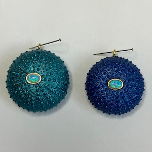 Może przedstawiać: Para kolczyków z motywem niebieskiego i ciemnoniebieskiego jeża morskiego z opalem w środku każdego.
