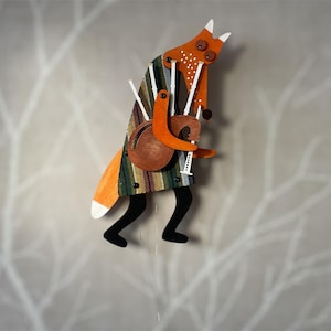 Peut inclure: Figurine en bois représentant un renard orange et blanc jouant d'un instrument de musique. Le renard porte un manteau à motifs et des jambes noires. Il tient un instrument marron avec des détails blancs. Objet décoratif.