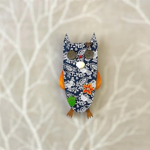 May include: A blue owl figurine with a floral pattern, orange wings, and various embellishments, including buttons and beads.