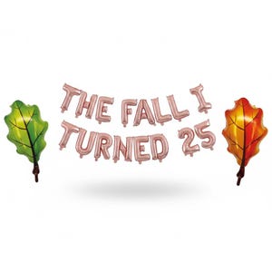 May include: A collection of rose gold foil balloons forming the phrase "THE FALL I TURNED 25", flanked by two leaf-shaped balloons. One leaf is green, the other is orange and yellow. Ideal for a 25th birthday celebration.