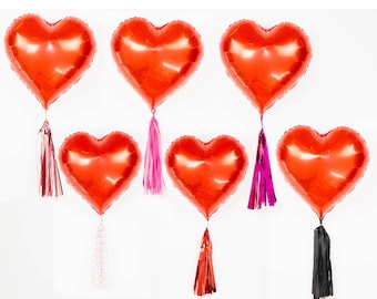 Puede incluir: Seis globos rojos en forma de corazón con borlas de diferentes colores. Las borlas son rosas, rojas y negras.