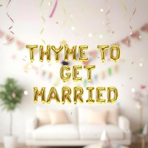 May include: Gold foil balloons spelling out "THYME TO GET MARRIED" float in front of a white wall. The scene is decorated with colorful confetti and streamers, suggesting a wedding or engagement celebration.
