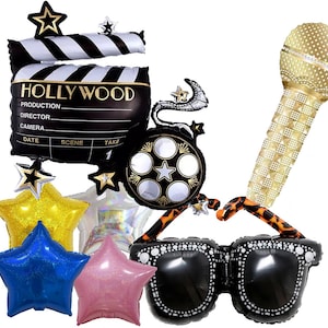 May include: A set of Hollywood-themed party balloons, including a clapperboard, a film reel, a microphone, sunglasses, and stars. The clapperboard has the word "HOLLYWOOD" printed on it, and the film reel has a star in the center. The microphone is gold and has a sparkly finish. The sunglasses are black with a white trim. The stars are gold, blue, and pink.