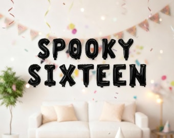 May include: Black foil balloon letters spelling "SPOOKY SIXTEEN" float above a white couch. The background includes a banner, confetti, and a small potted plant, creating a festive atmosphere for a Halloween or birthday celebration.