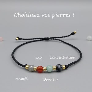 Peut inclure: Un bracelet en cordon noir avec sept perles, dont des perles grises, rouges, vertes et noires. Le bracelet porte les mots "Amitié", "Joie", "Bonheur" et "Concentration".