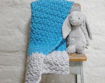 May include: A blue and white crocheted baby blanket draped over a wooden chair with a gray plush bunny sitting on the seat.
