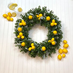 May include: A green wreath with faux lemons, perfect for a summery decor theme.