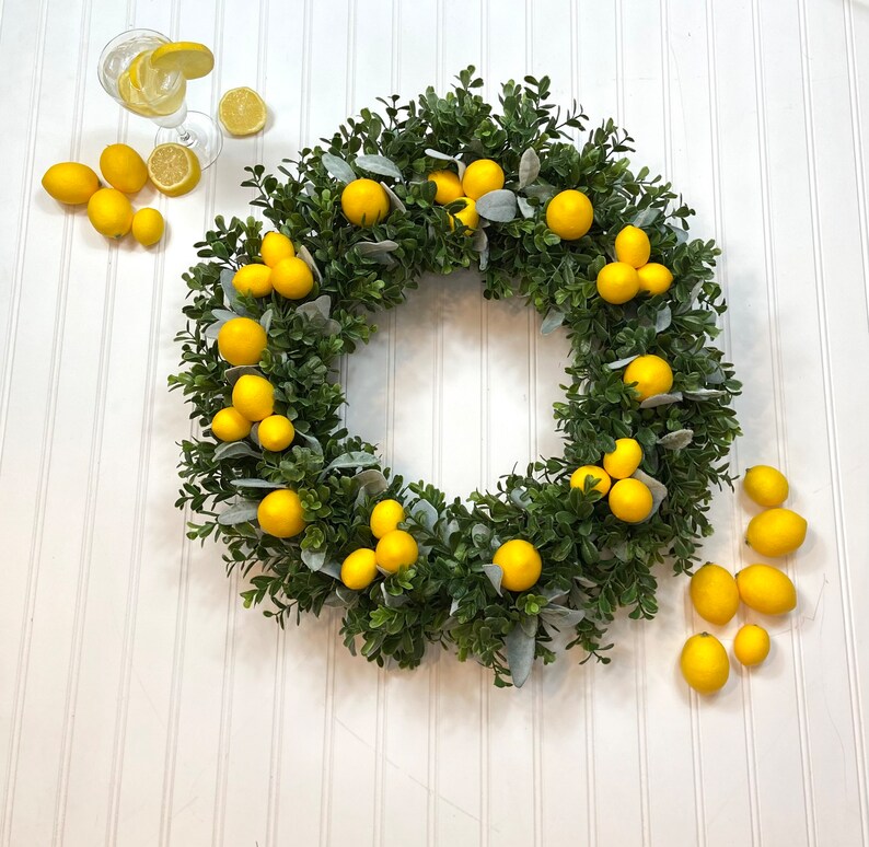 May include: A green wreath with faux lemons, perfect for a summery decor theme.