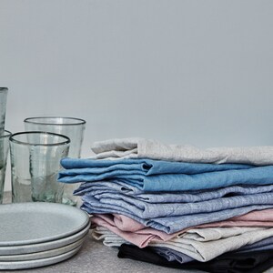 a pile of kitchen linens next to glasses and plates